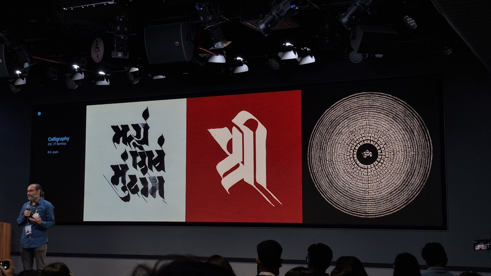 A speaker presenting Devanagari calligraphy on the main screen